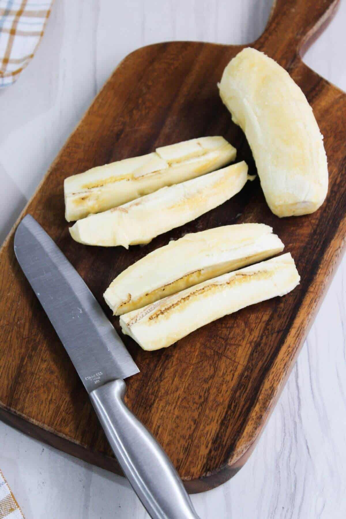 Sliced bananas on a cutting board with a knife.