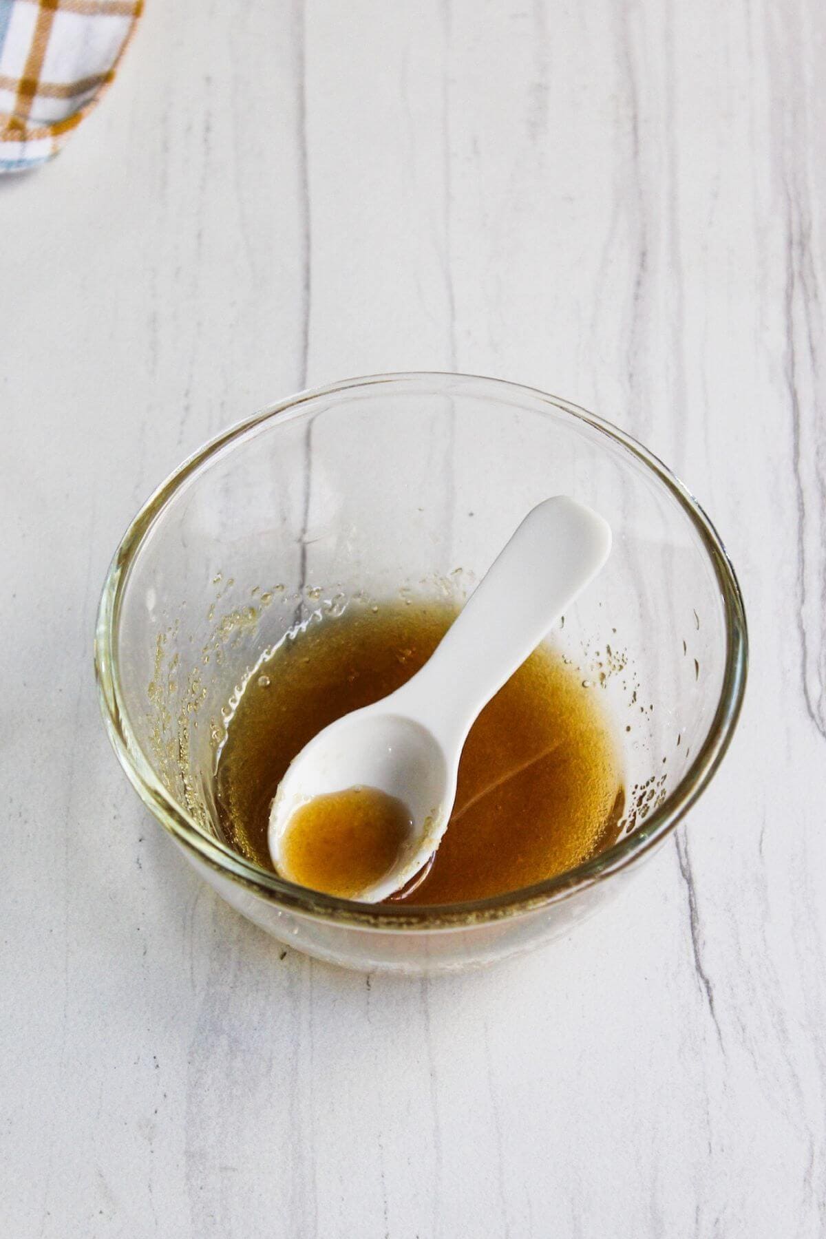 A glass bowl of brown sugar glaze with spoon.