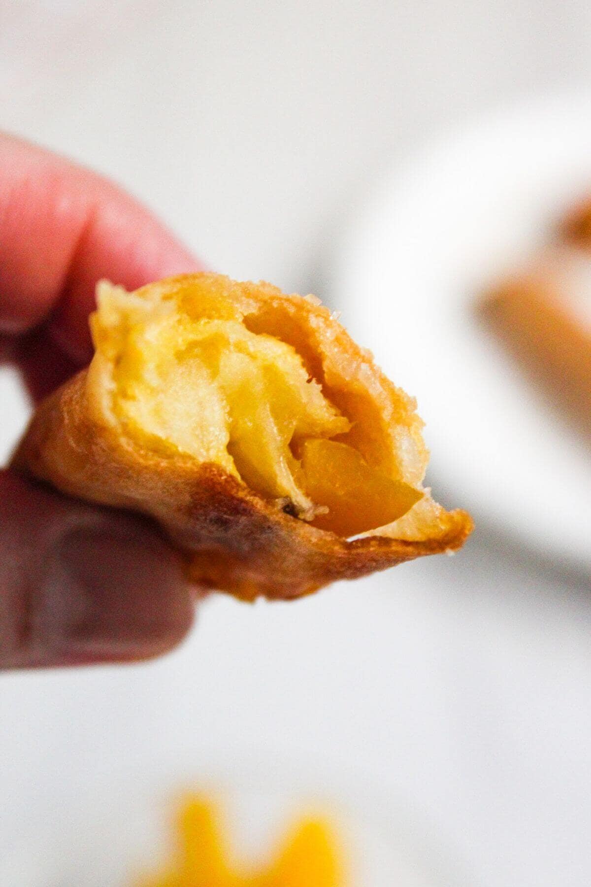 A person holds a piece of a banana turon and shows the inside.