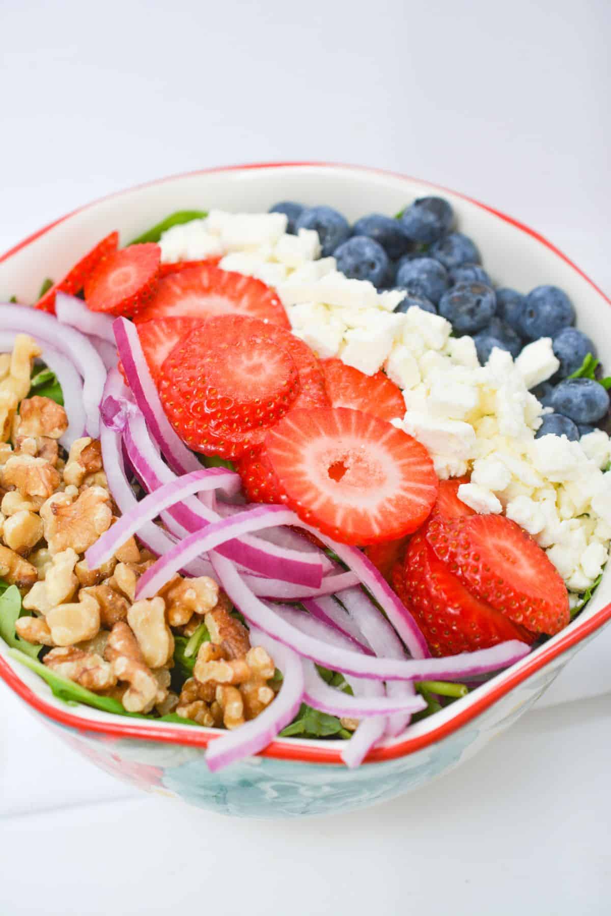 A salad with strawberries, blueberries and walnuts.
