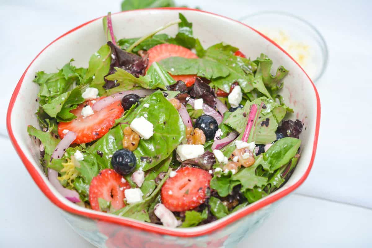 A salad with strawberries, blueberries and feta cheese.