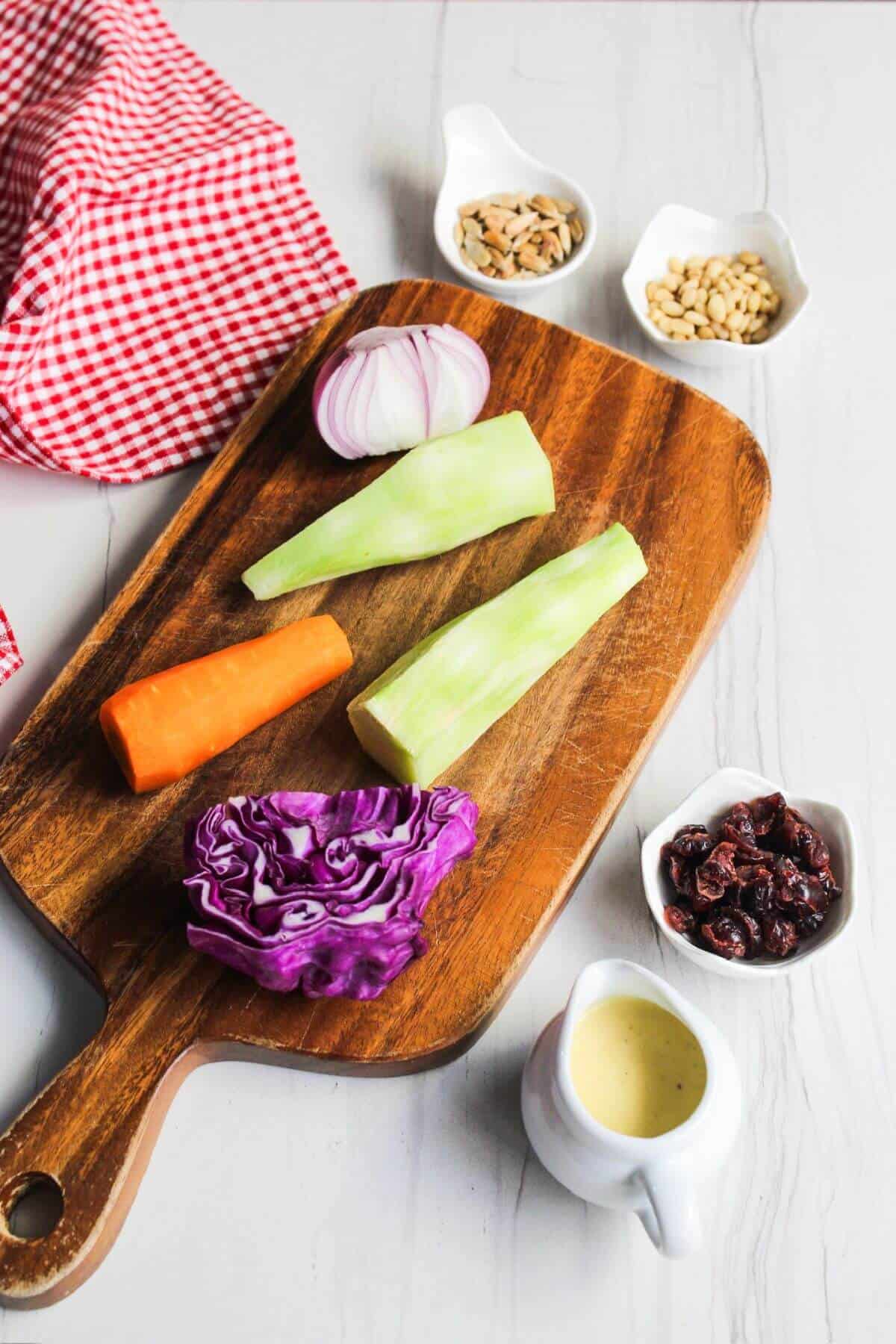 A wooden cutting board with broccoli slaw ingredients.