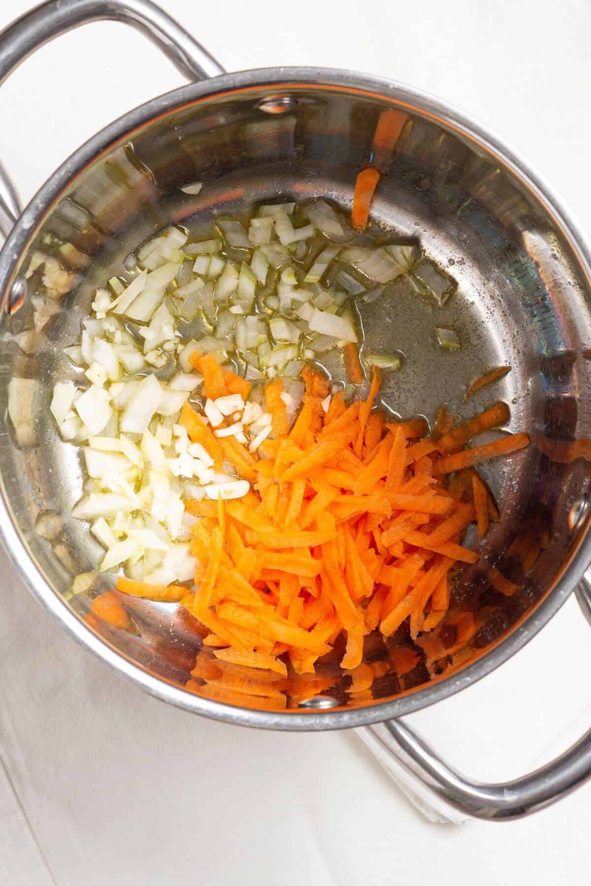 Carrots, onions, and garlic added to soup pot.