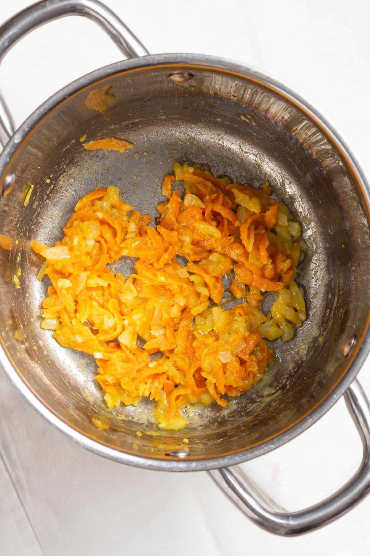 Cooked carrot and onion mixture in pot.