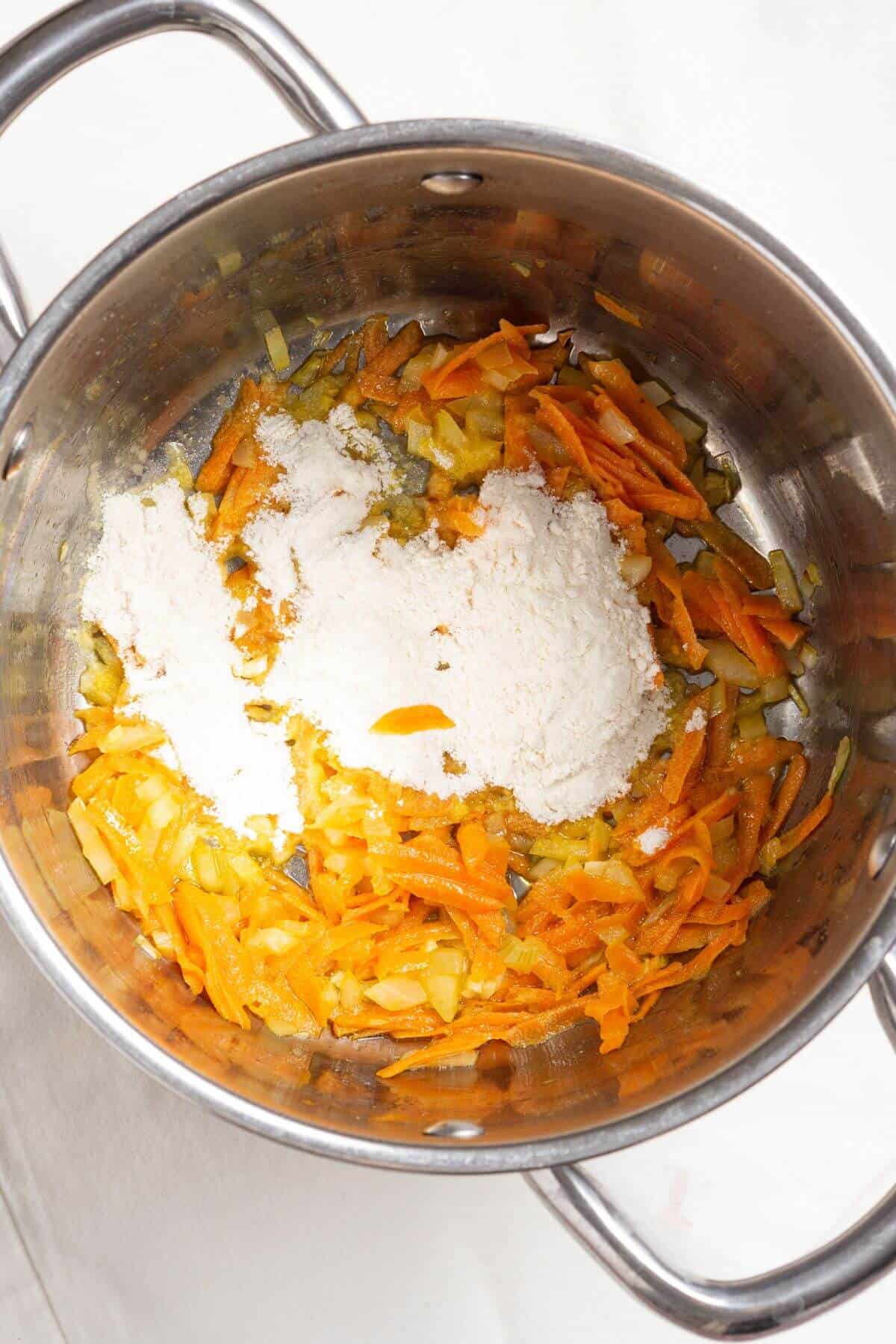 Flour added to vegetables in pot.