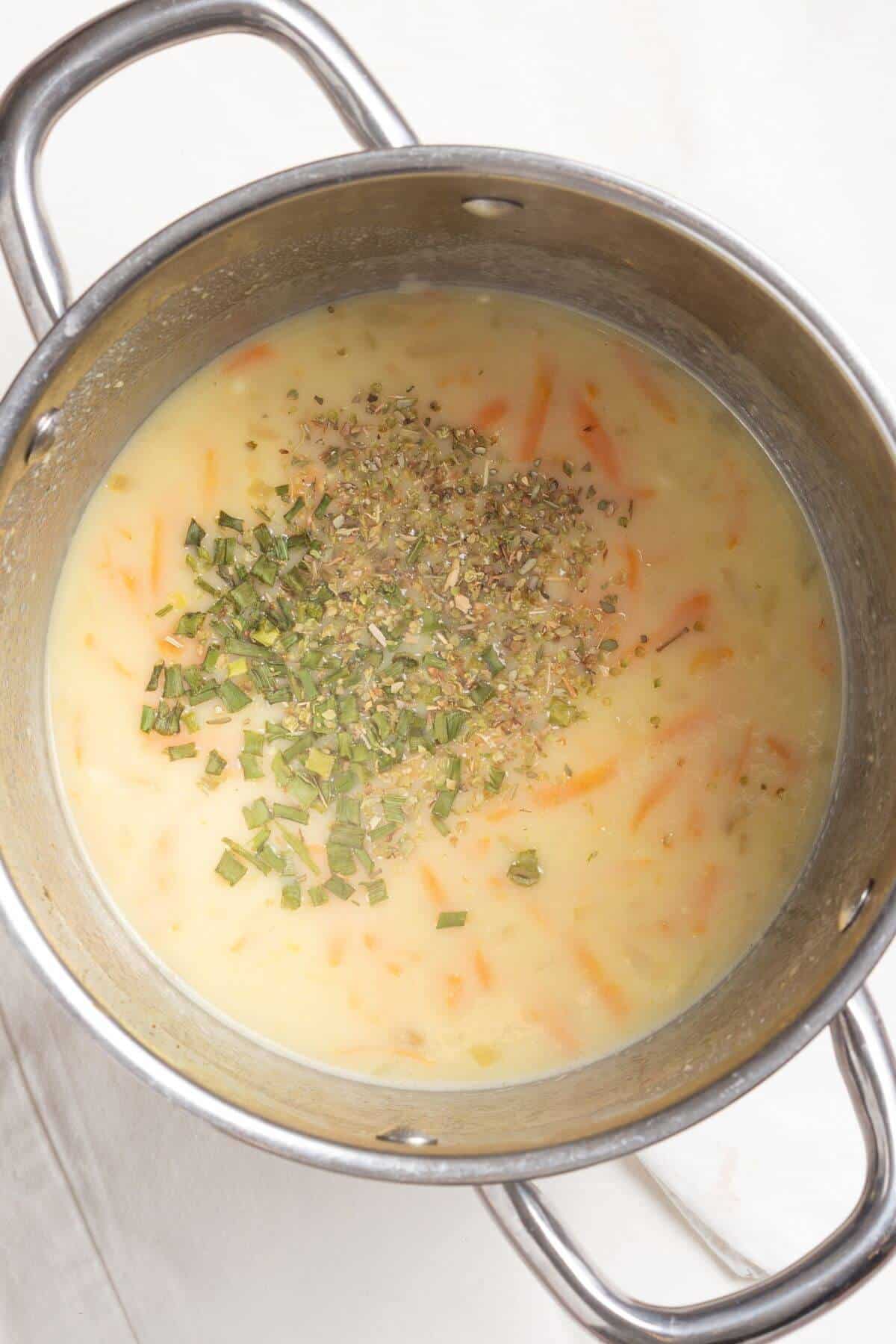 Milk and spices added to soup in pot.