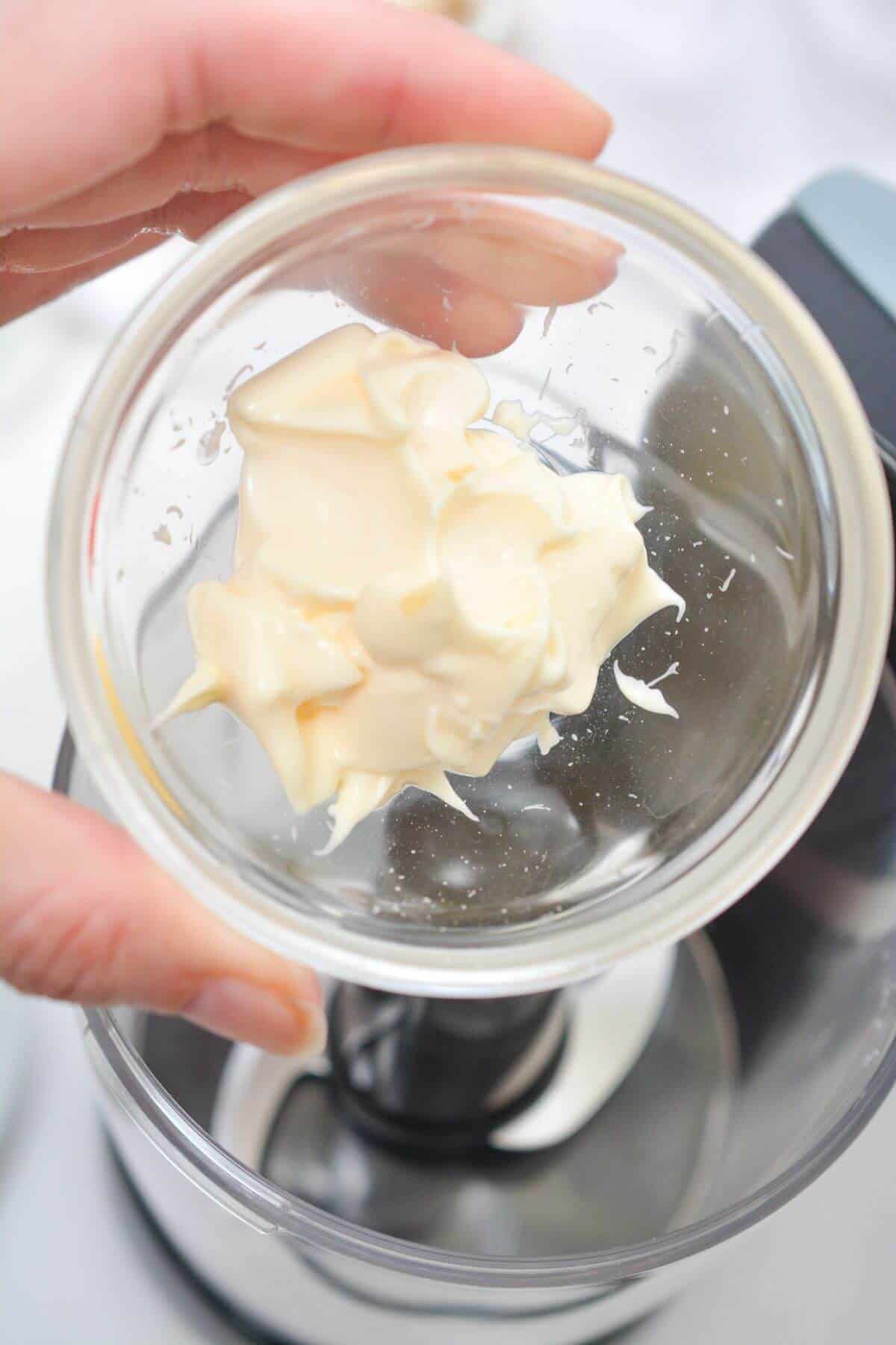 Adding mayonnaise to small food processor container.