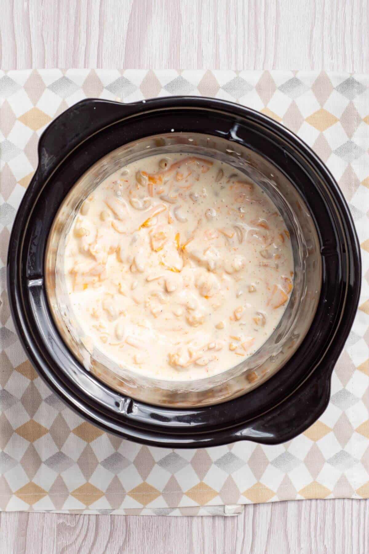 A crock pot with a mac and cheese mixture.
