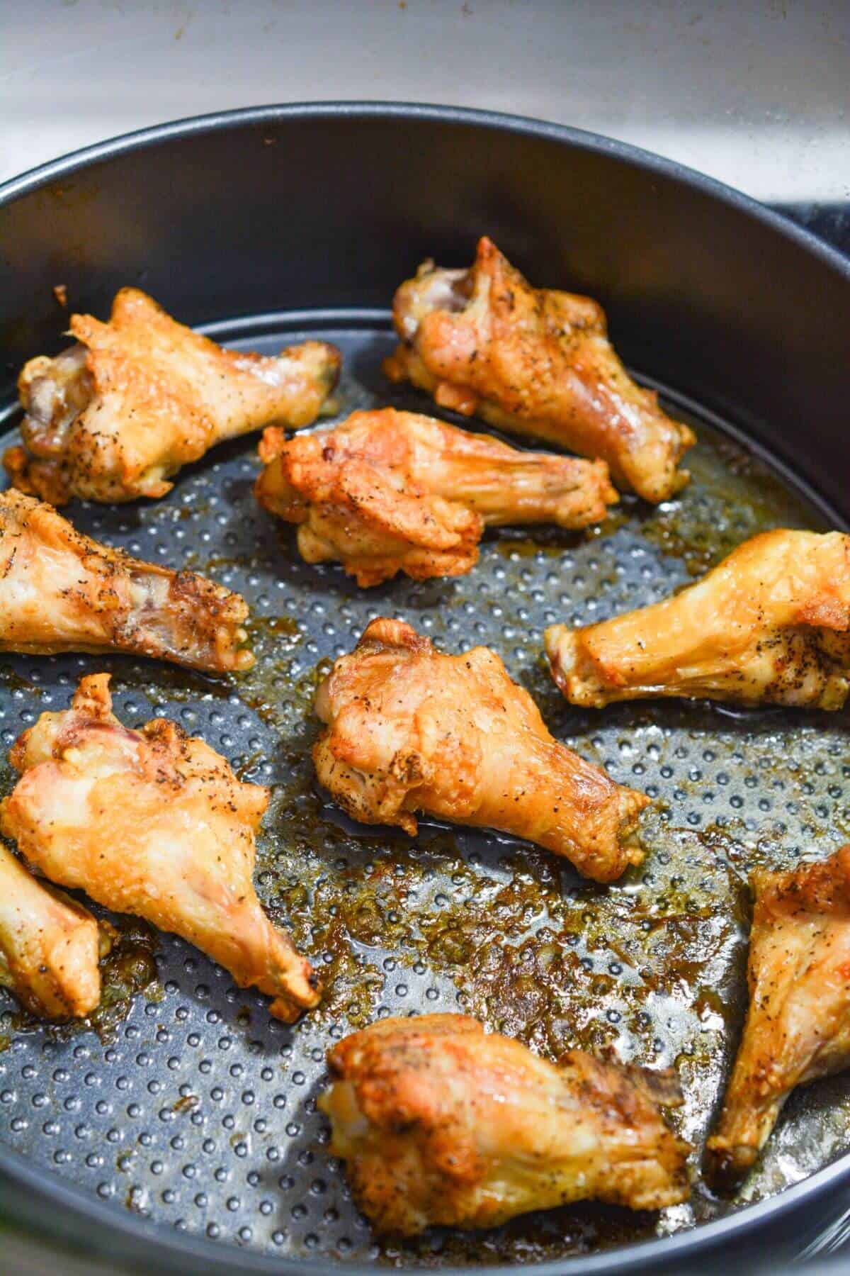 Cooked wings in round baking pan.