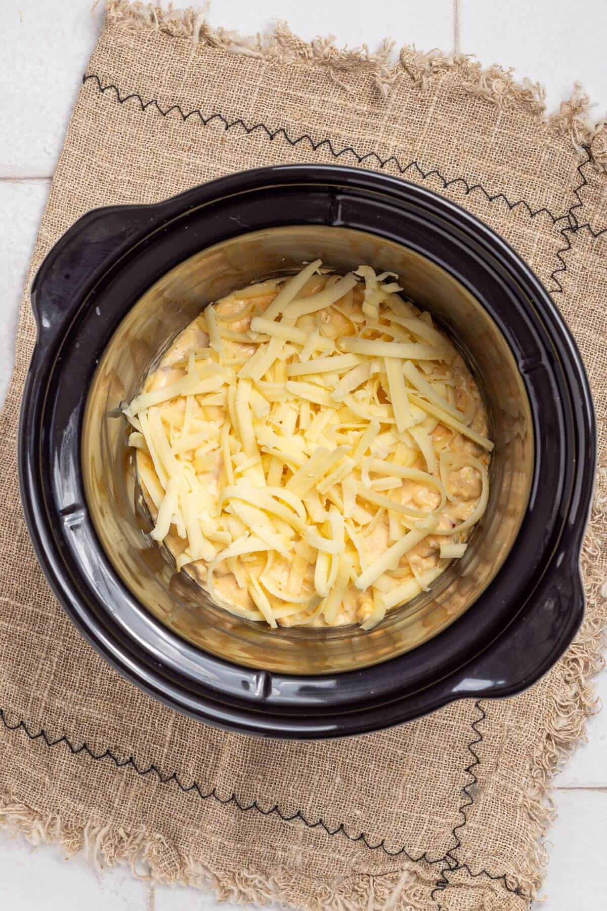 Shredded cheese added to slow cooker crock pot.