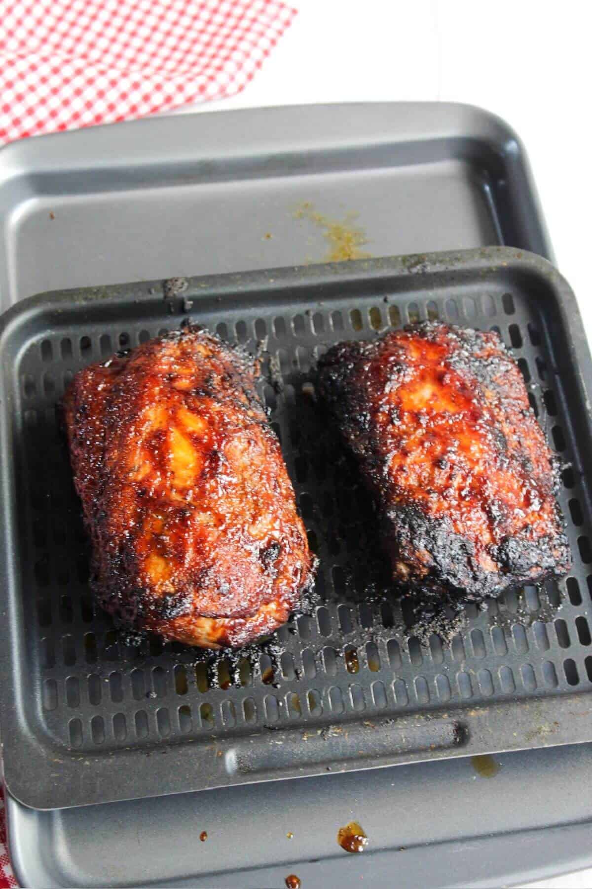 Two pieces of BBQ pork ribs on an air fryer tray.