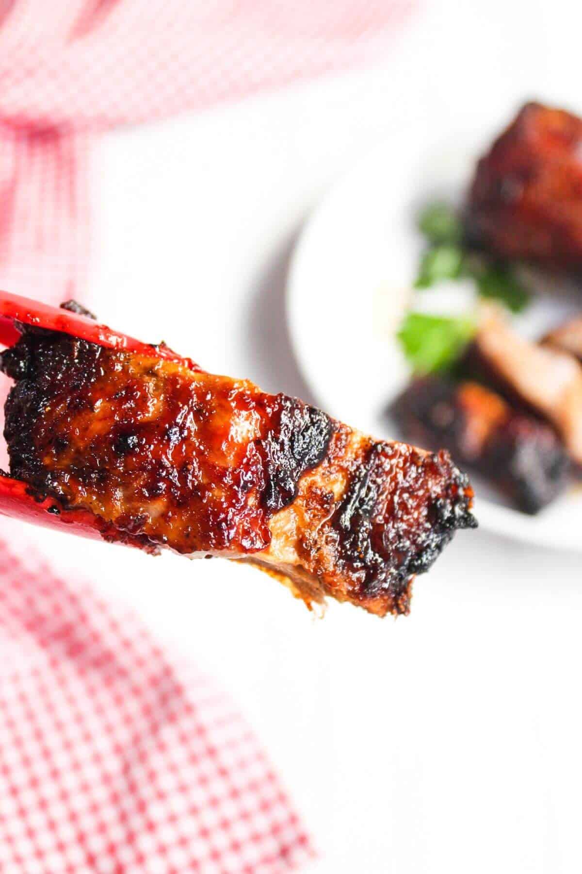 BBQ ribs on a plate with a red and white checkered napkin.