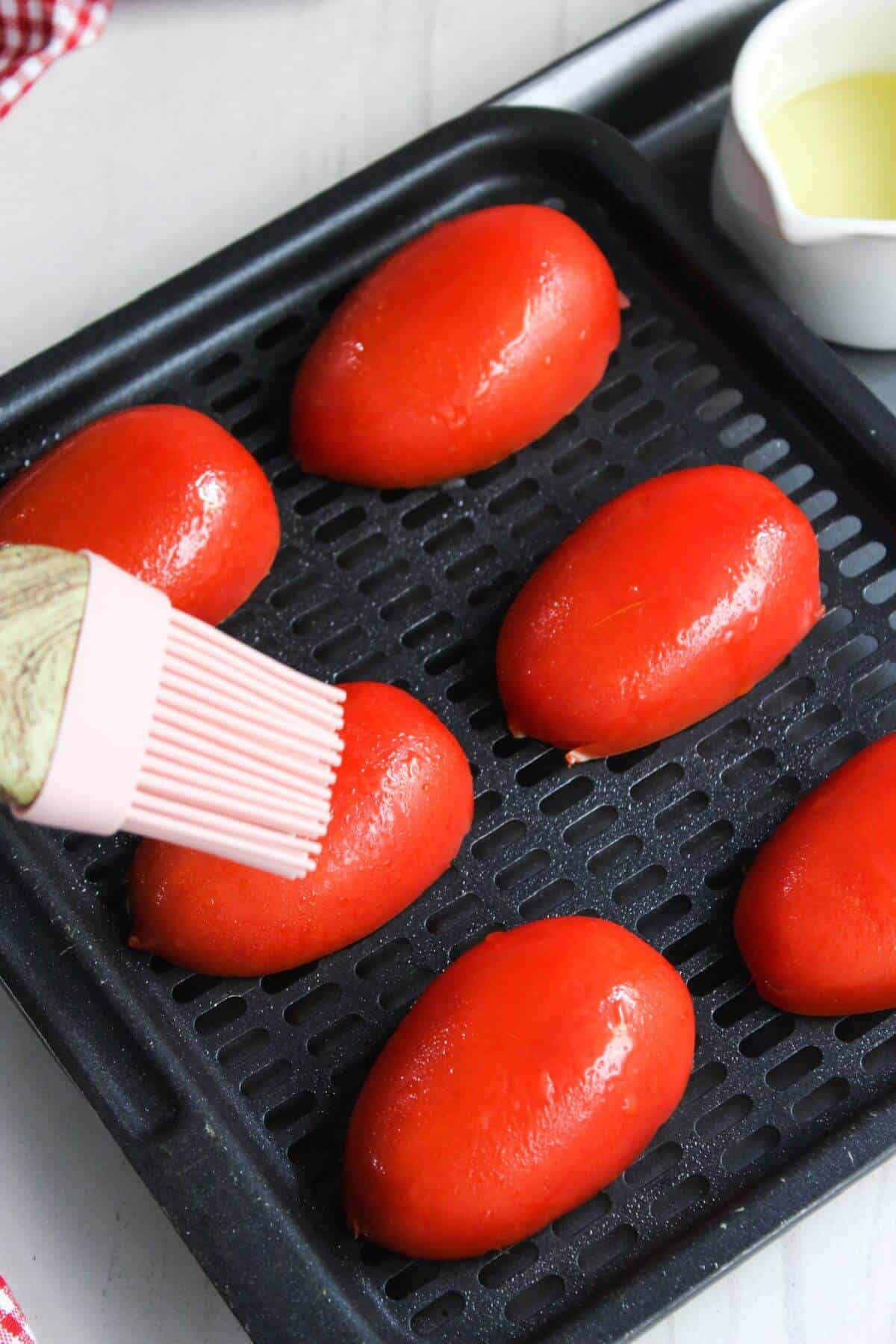 A pan with tomatoes on it and a brush on it.