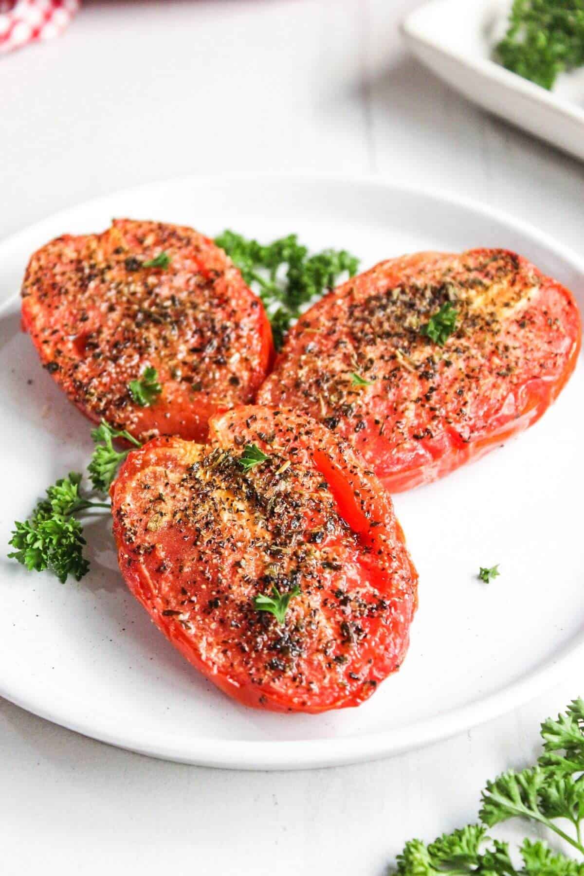 Air fryer roasted tomatoes on a white plate with parsley.