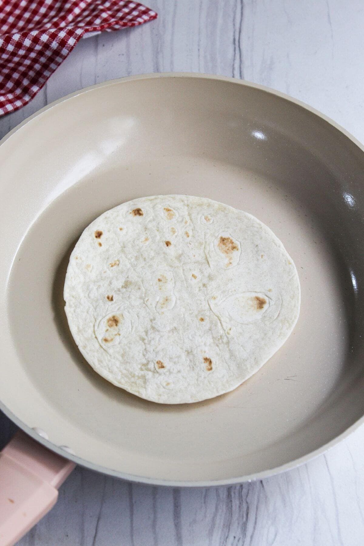 A tortilla is being cooked in a pan for ground pork tacos.