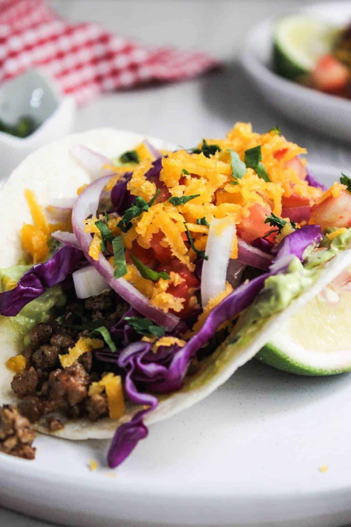 A plate of ground pork tacos on a white plate.