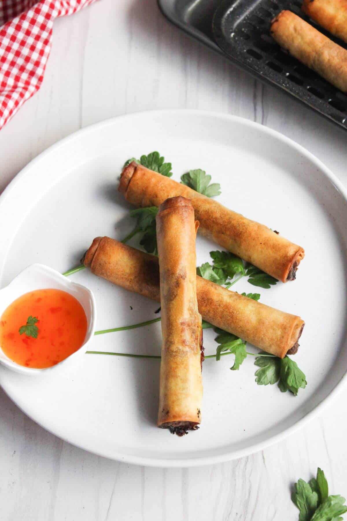 Filipino lumpia shanghai on a plate with dipping sauce.