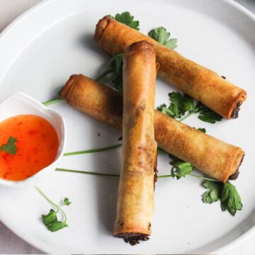 Filipino lumpia on a plate with dipping sauce.