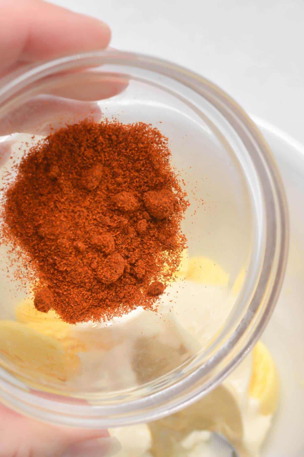 A person is holding a bowl of paprika in their hand.