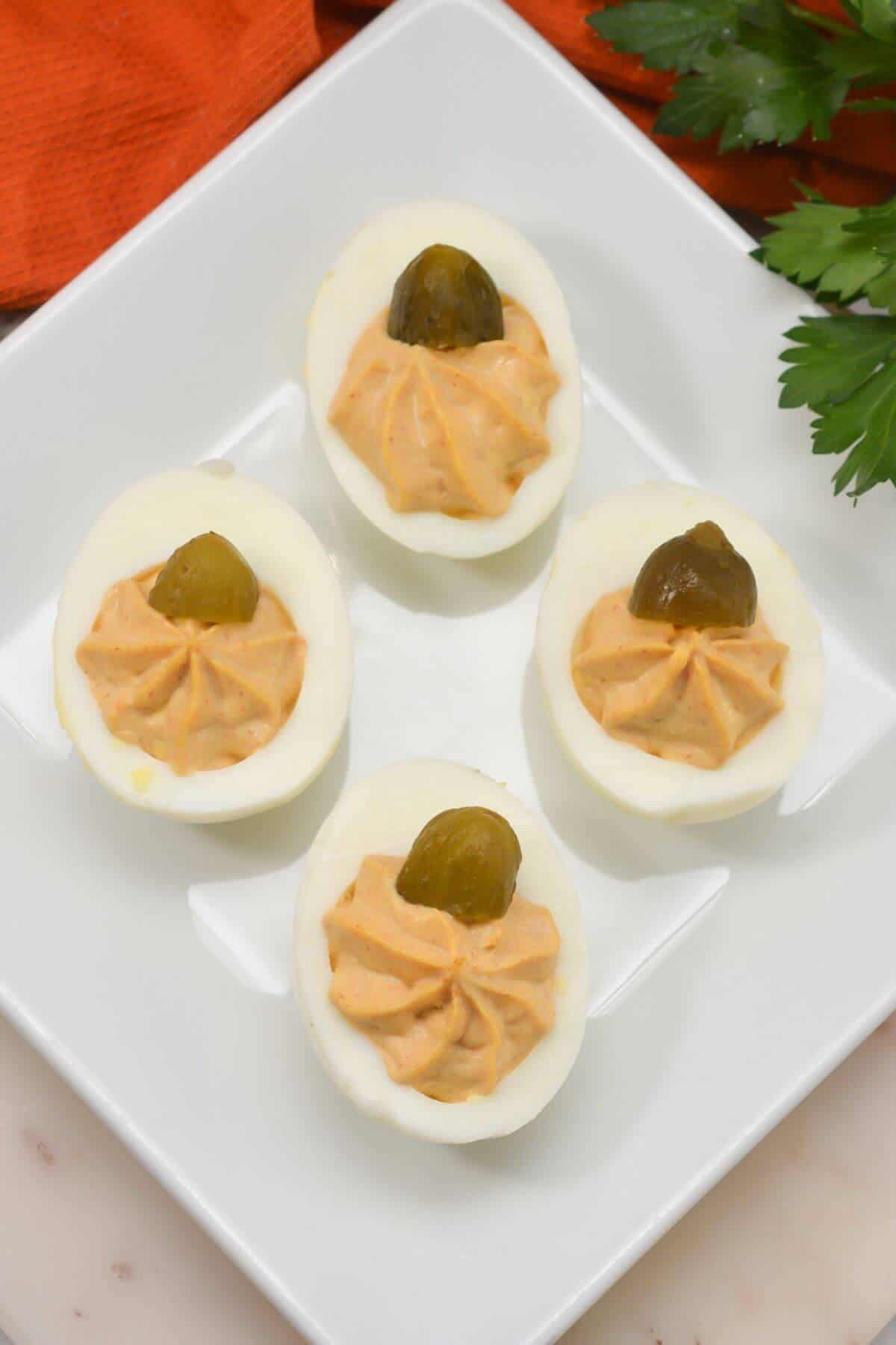 Thanksgiving pumpkin deviled eggs with on a white plate.