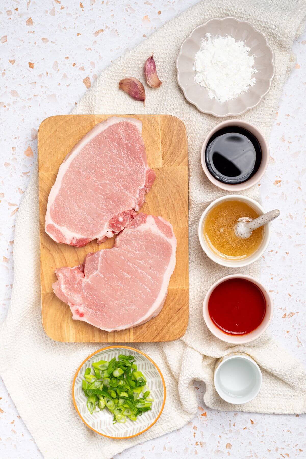 Pork chops on a cutting board with sauces and other ingredients.