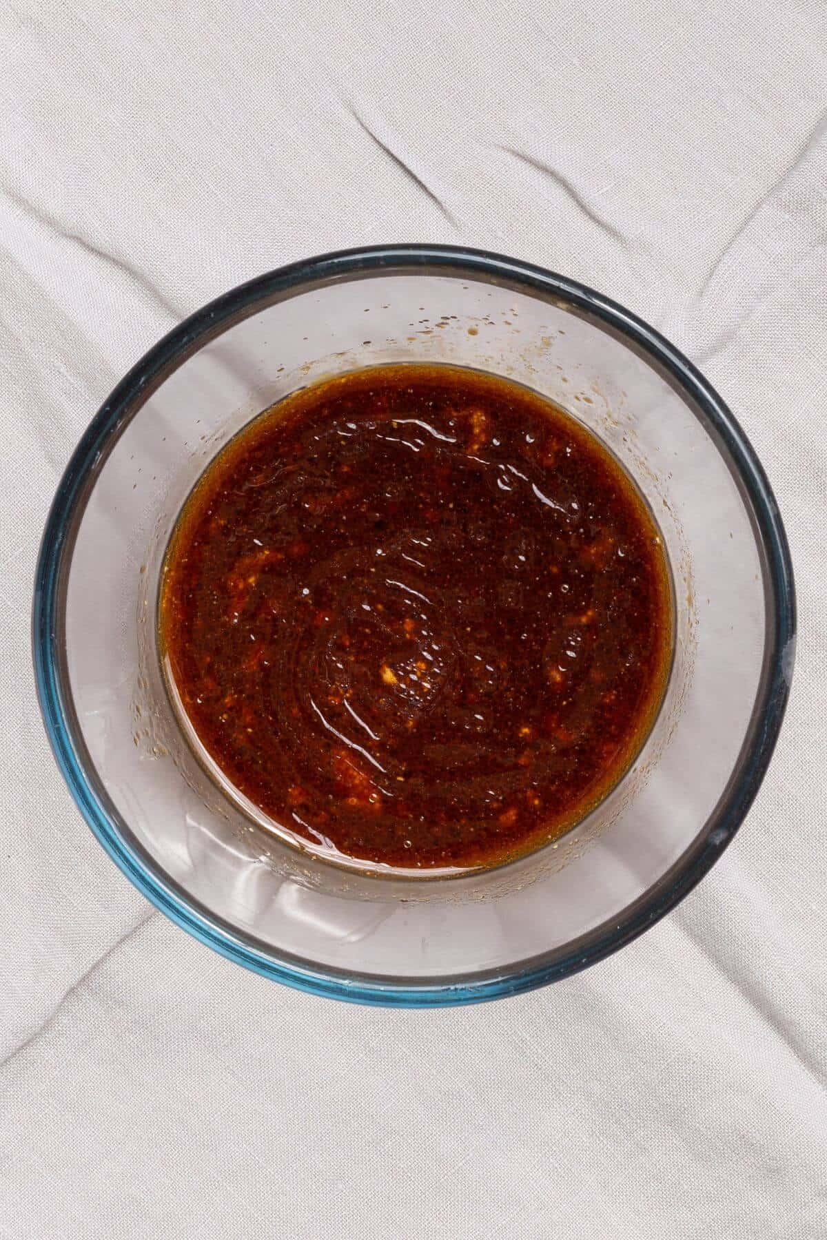 A bowl of sauce on a white cloth.