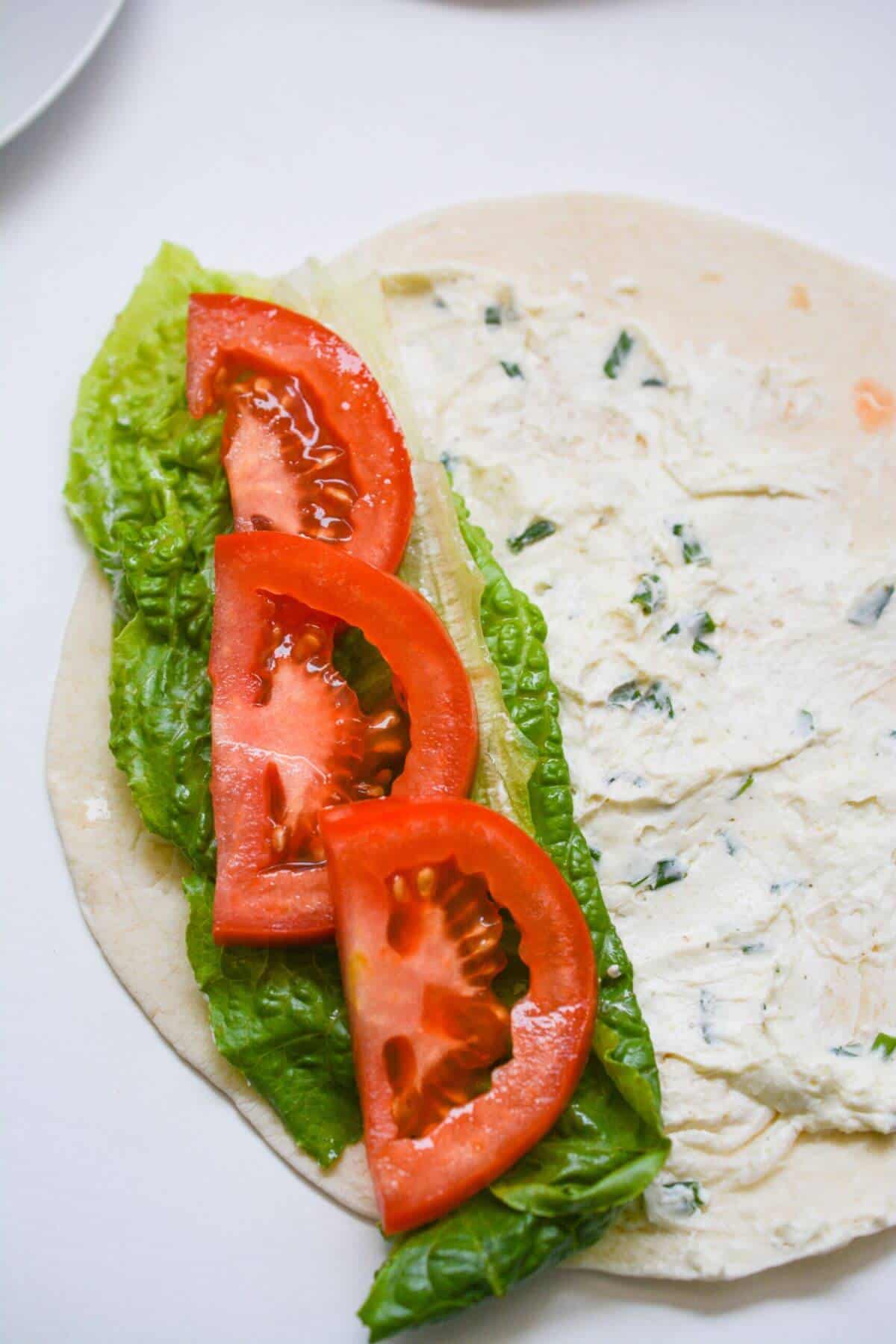 A tortilla with tomatoes and lettuce on it.