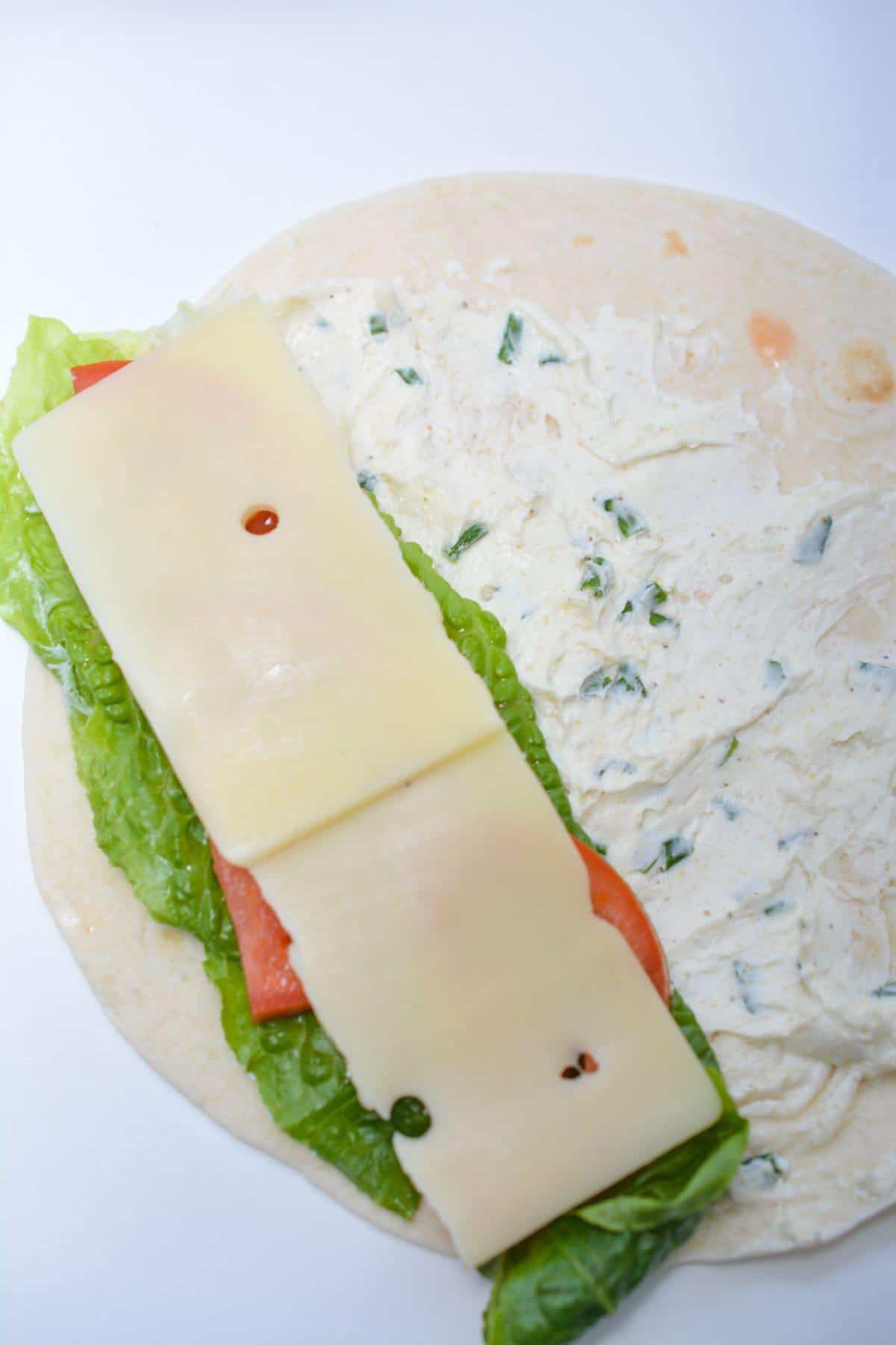 A tortilla with cheese, lettuce and tomatoes.