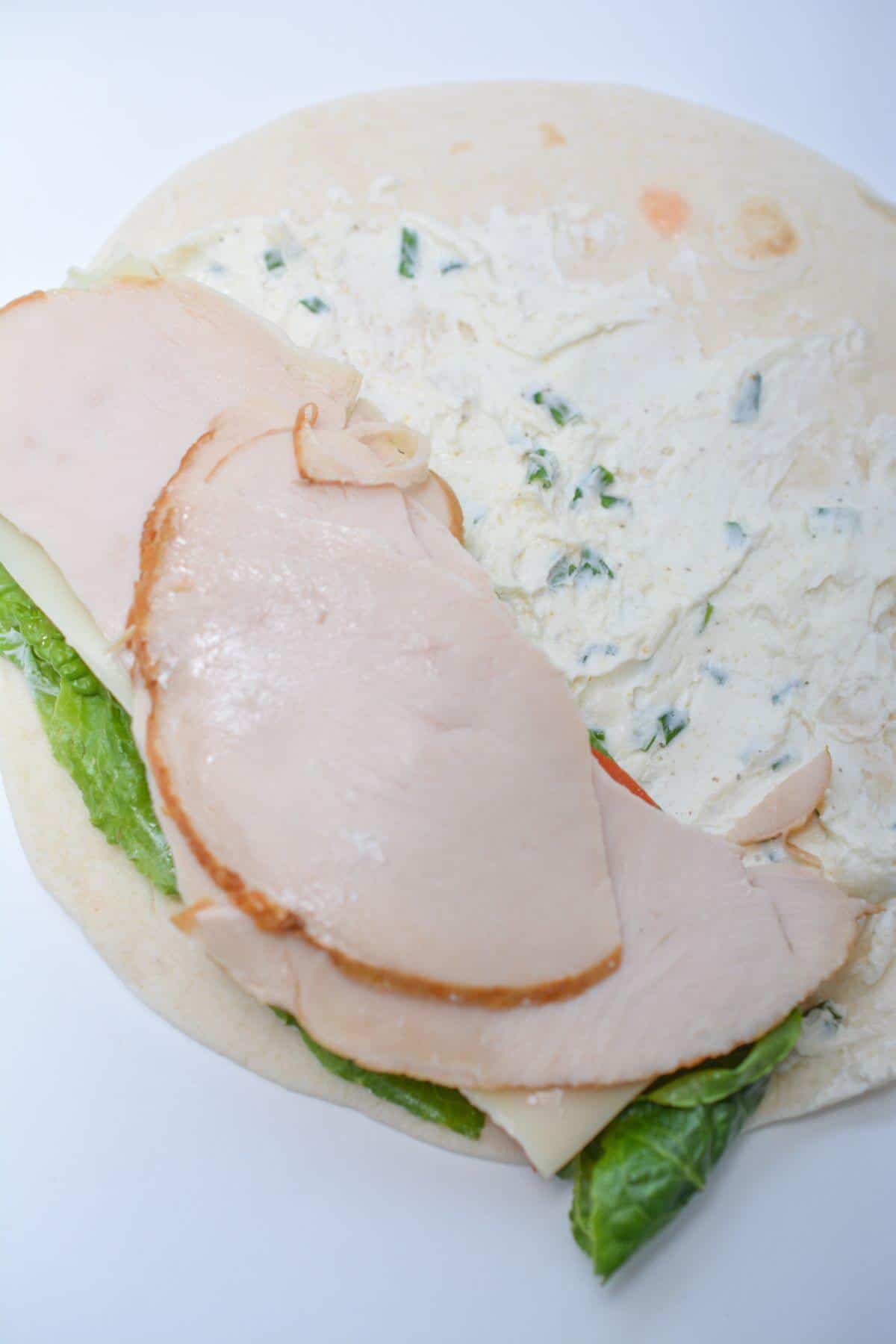 A turkey wrap with lettuce and cheese on a white background.