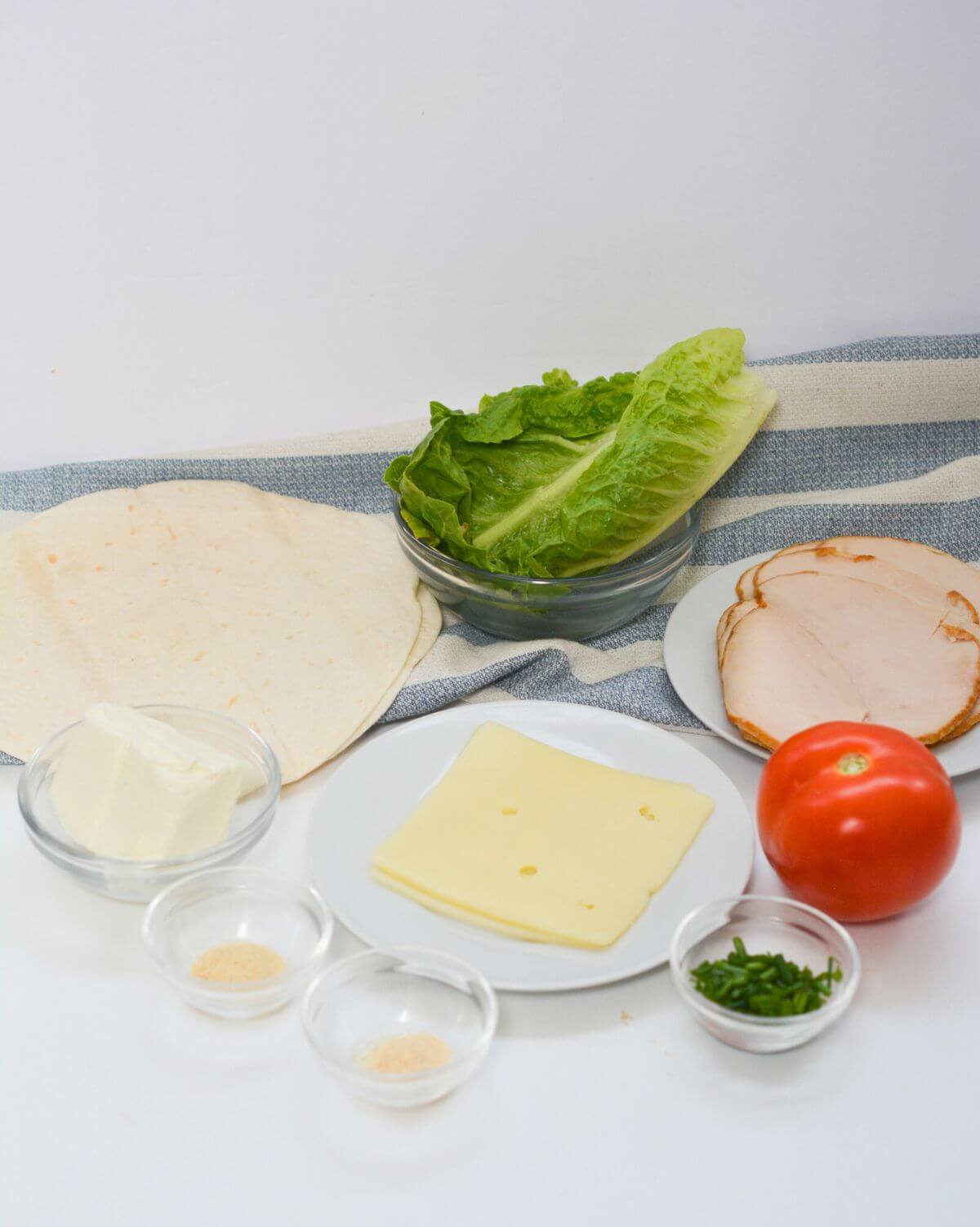 A plate with cheese, tomatoes, lettuce and other ingredients.