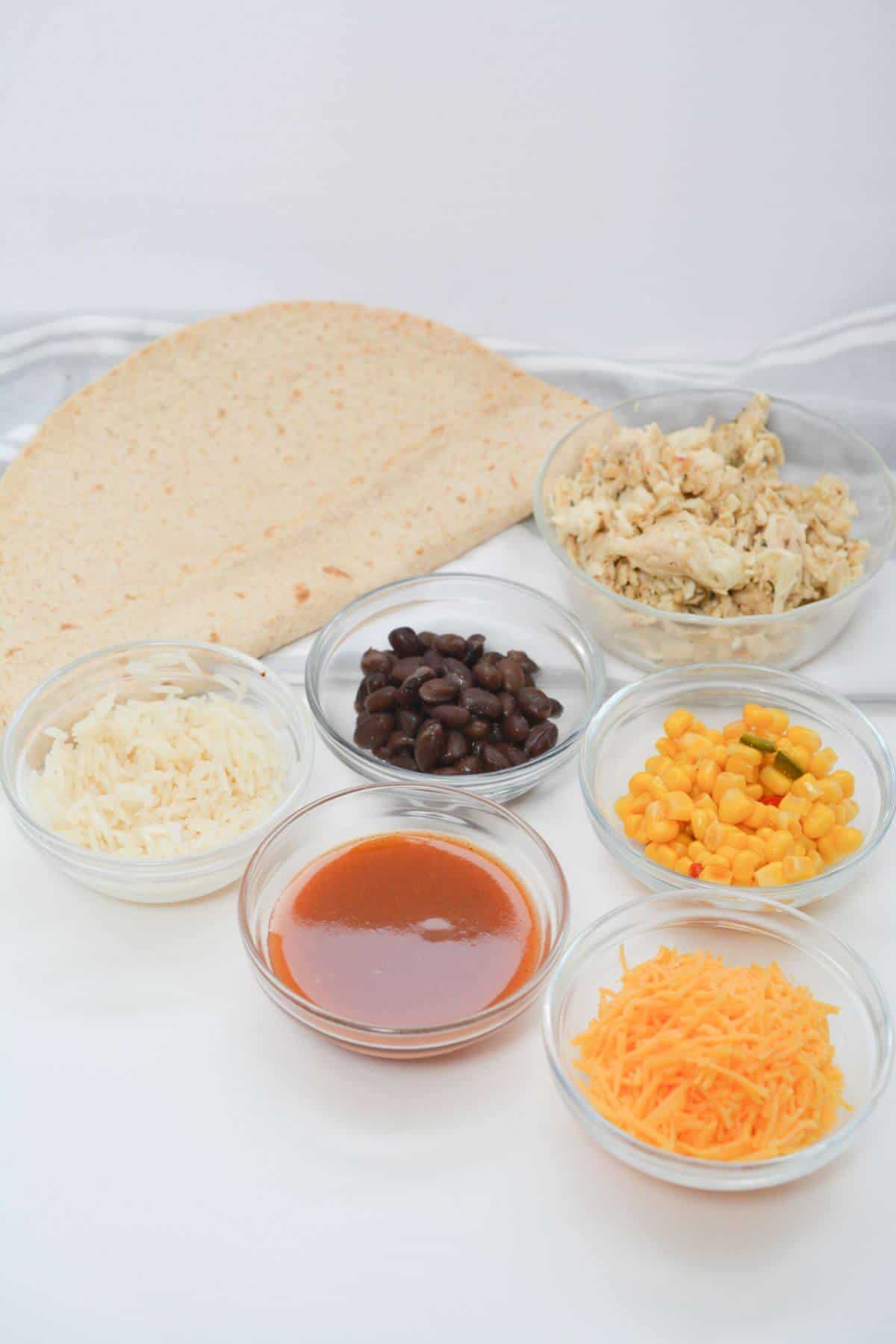 The ingredients for a Mexican wet burrito are laid out on a table.