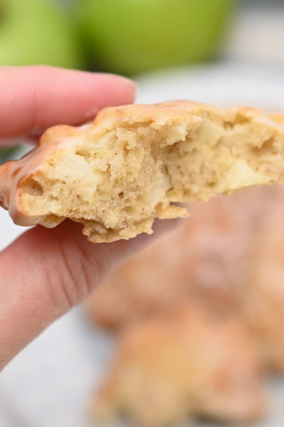 A person holding up a piece of apple fritter.