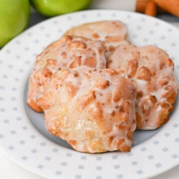 Apple fritters on a plate with apples and cinnamon sticks, made with an air fryer.