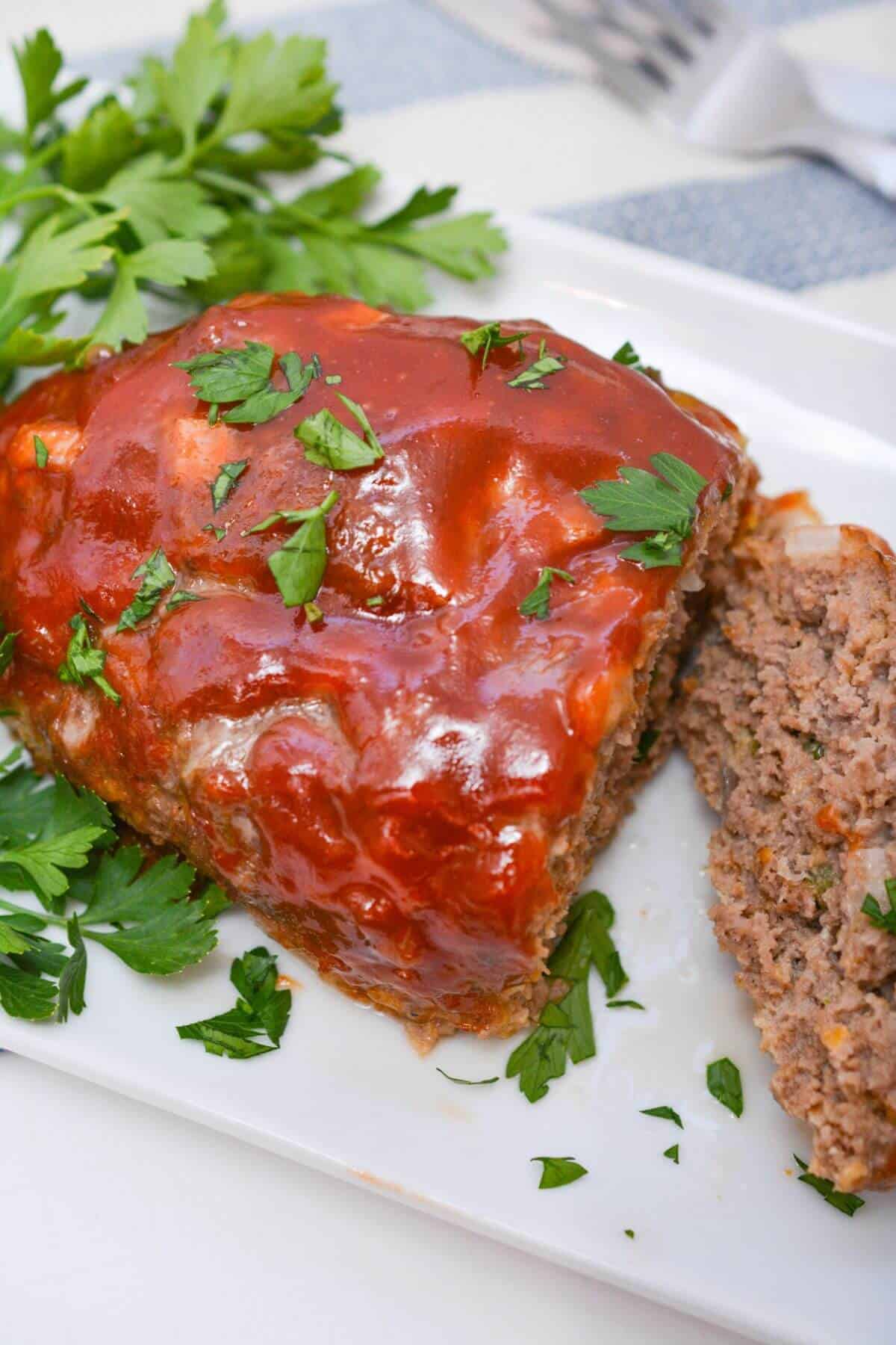 Meatloaf on a white platter with parsley.