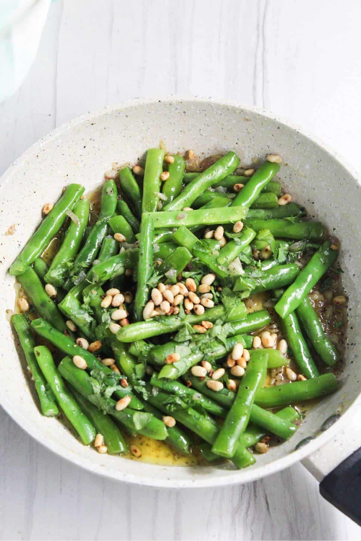 Green beans in a pan with pine nuts.