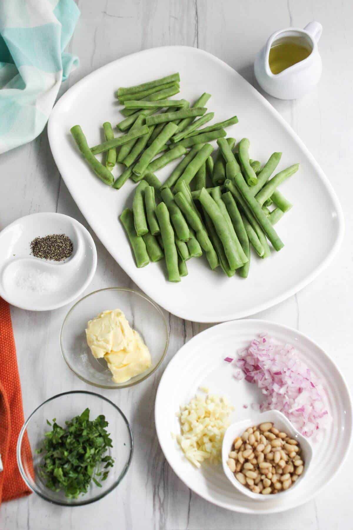 Ingredients for green beans with garlic butter on a white table.