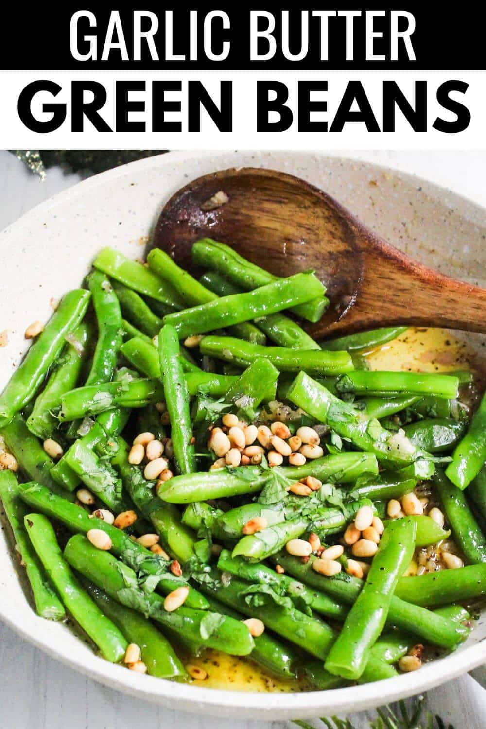 Garlic butter green beans in a bowl with a wooden spoon.