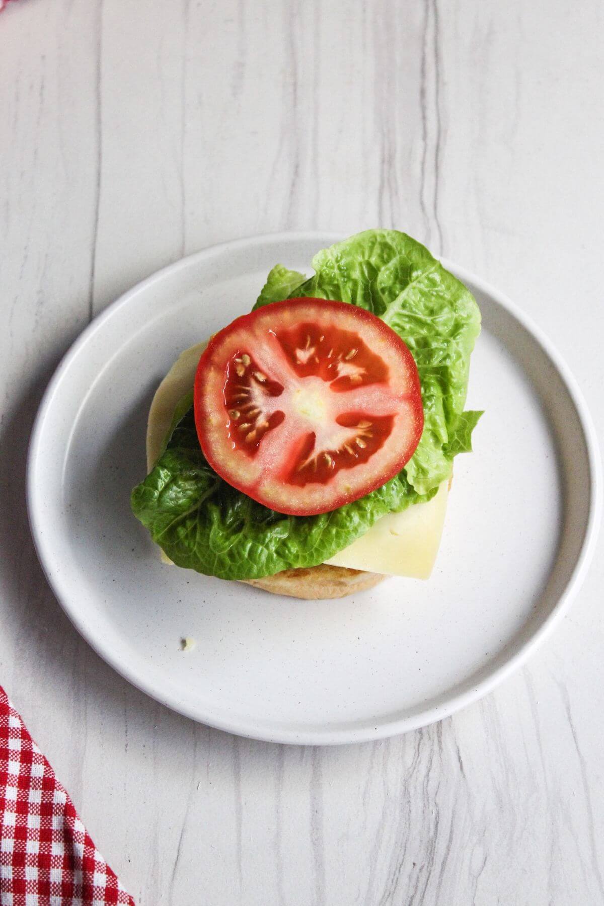A burger with lettuce and tomato on a plate.