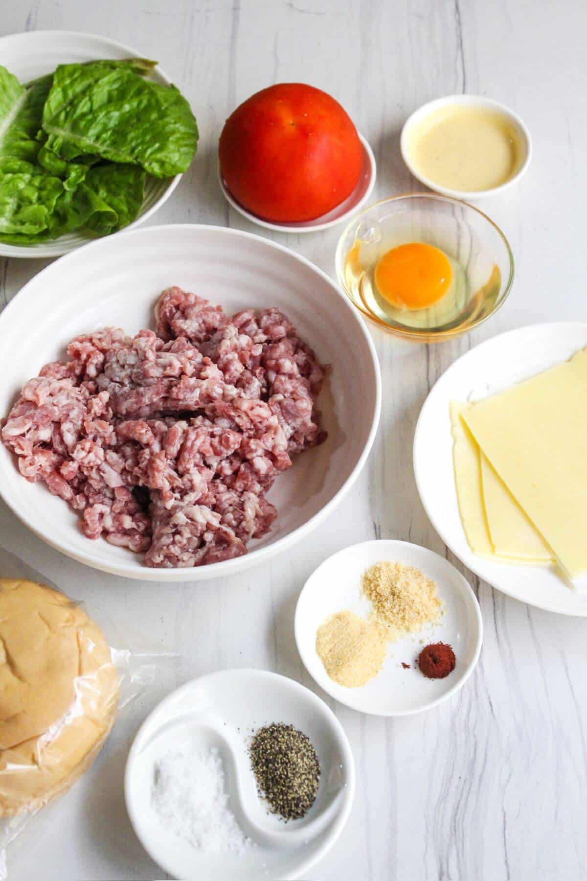 The ingredients for a pork burgers are laid out on a table.