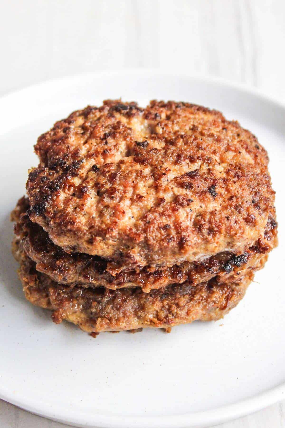 A stack of meat patties on a white plate.