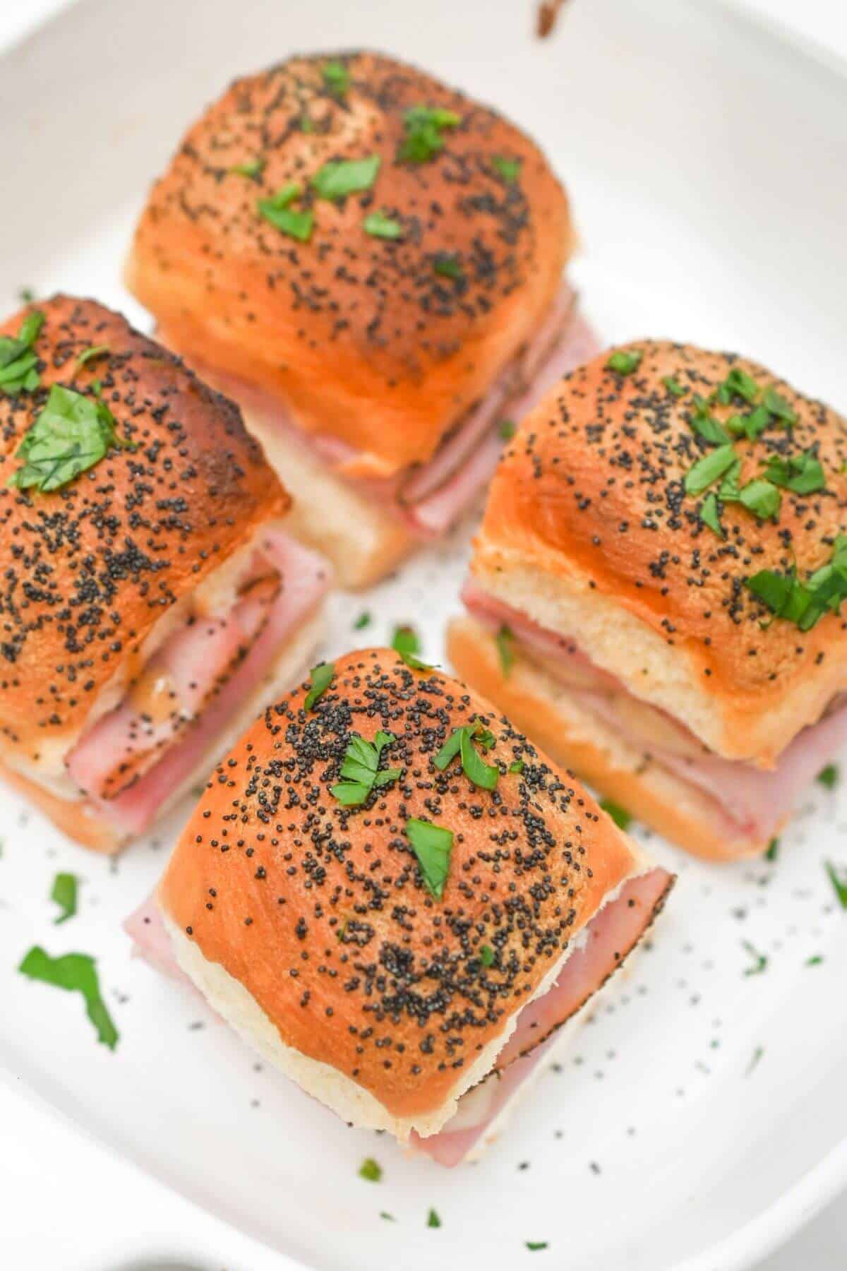 Ham and cheese sliders on a white plate.