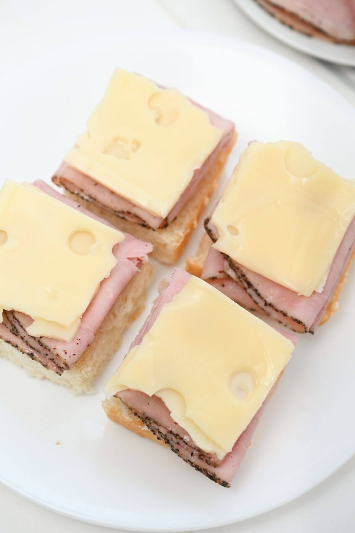 Four slices of ham and cheese on a plate.