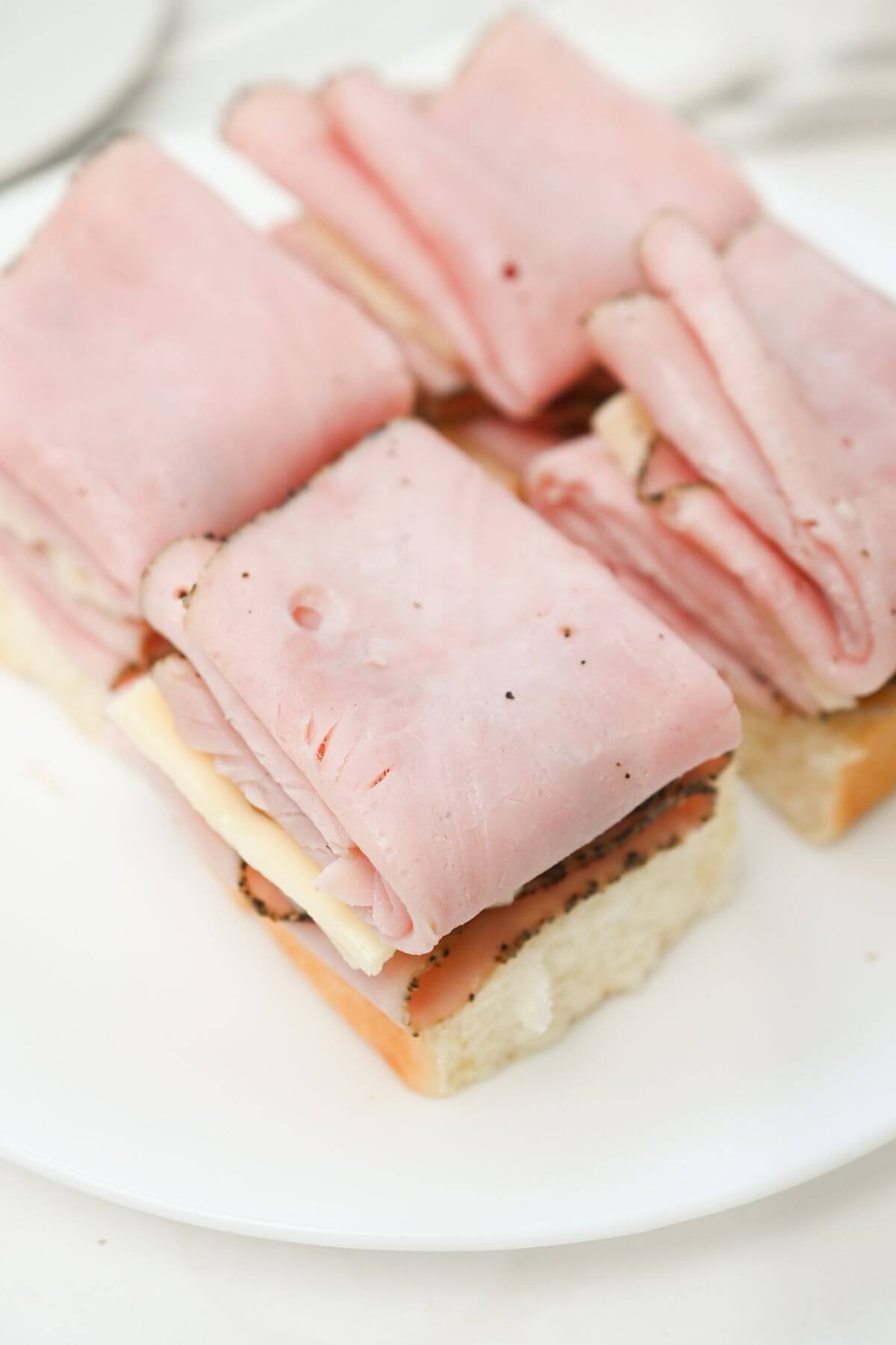 Ham and cheese sandwich on a white plate.