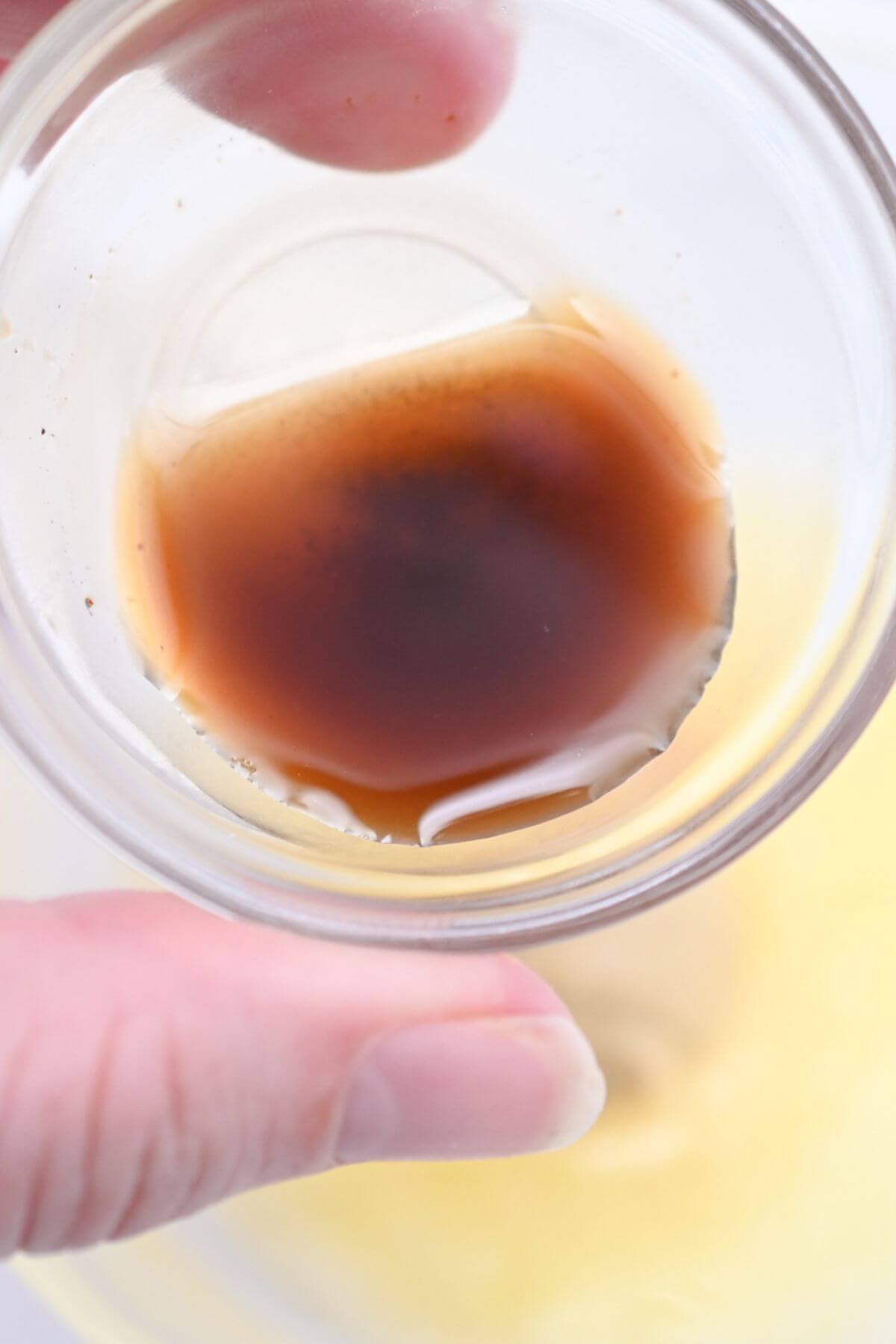 A person holding a glass with brown liquid in it.