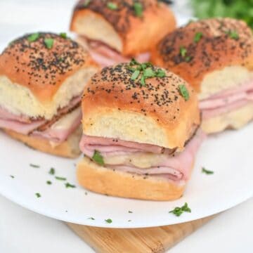 Ham and cheese sliders on a white plate.