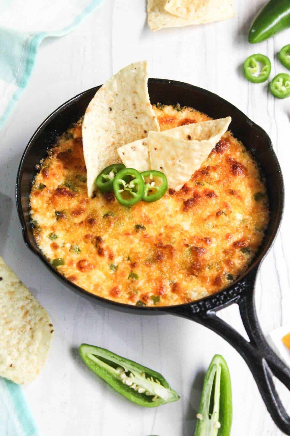 Jalapeño popper cheese dip in a skillet with jalapeños and tortilla chips.