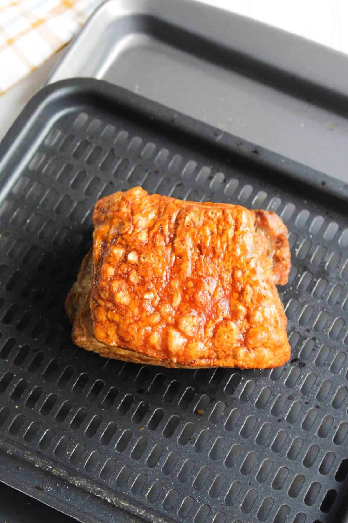 A piece of air-fried pork belly on air fryer tray.