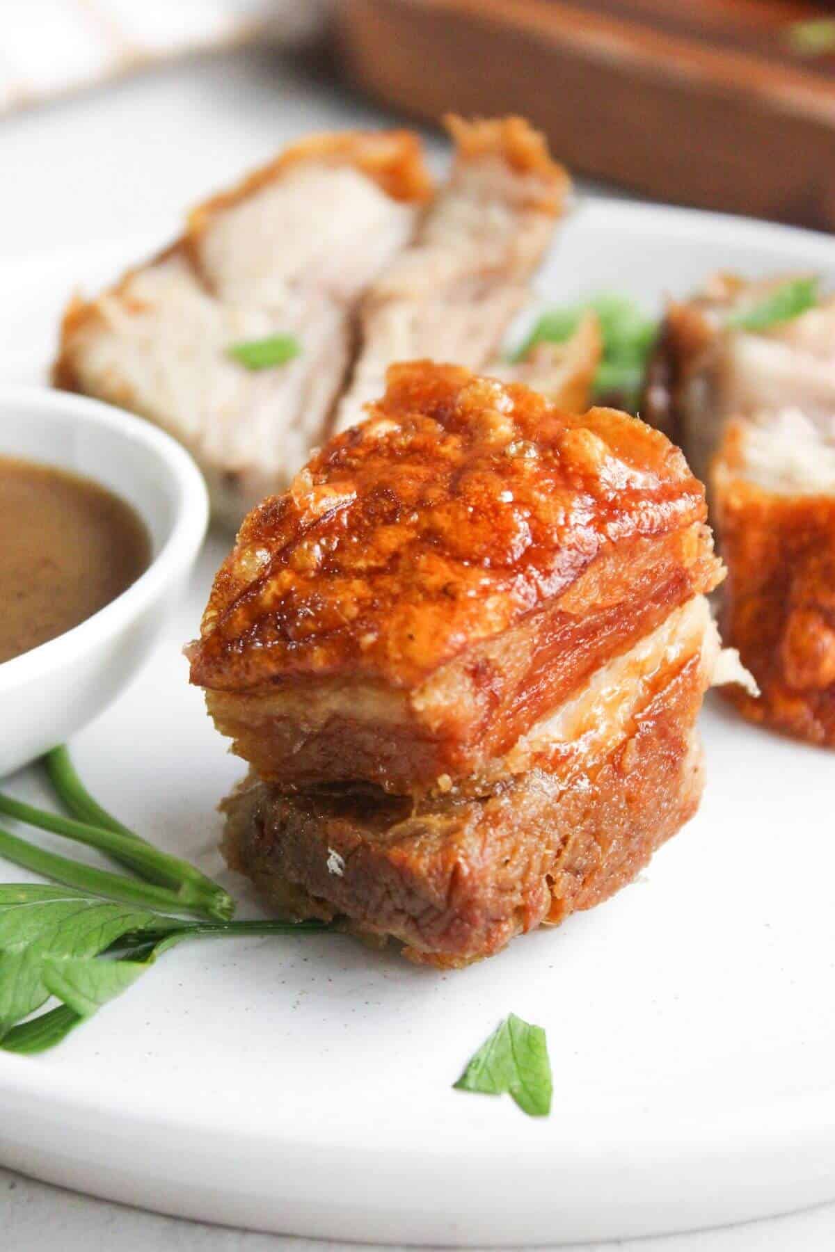 Lechon kawali with sauce on a white plate.