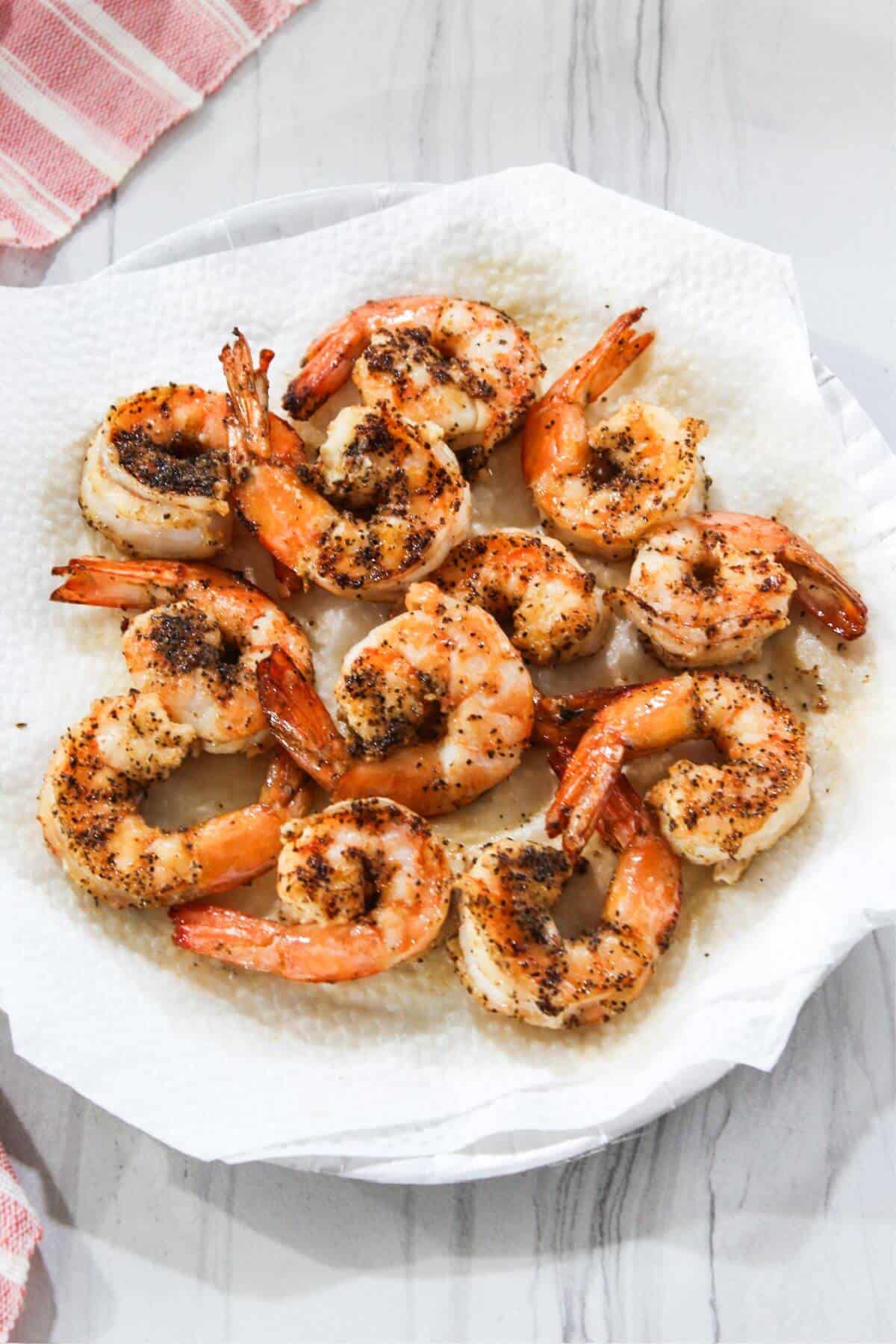 Grilled shrimp on a white plate with a red napkin.
