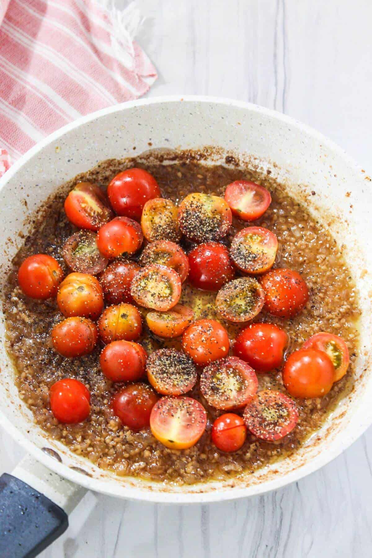 A frying pan filled with tomatoes and spices.